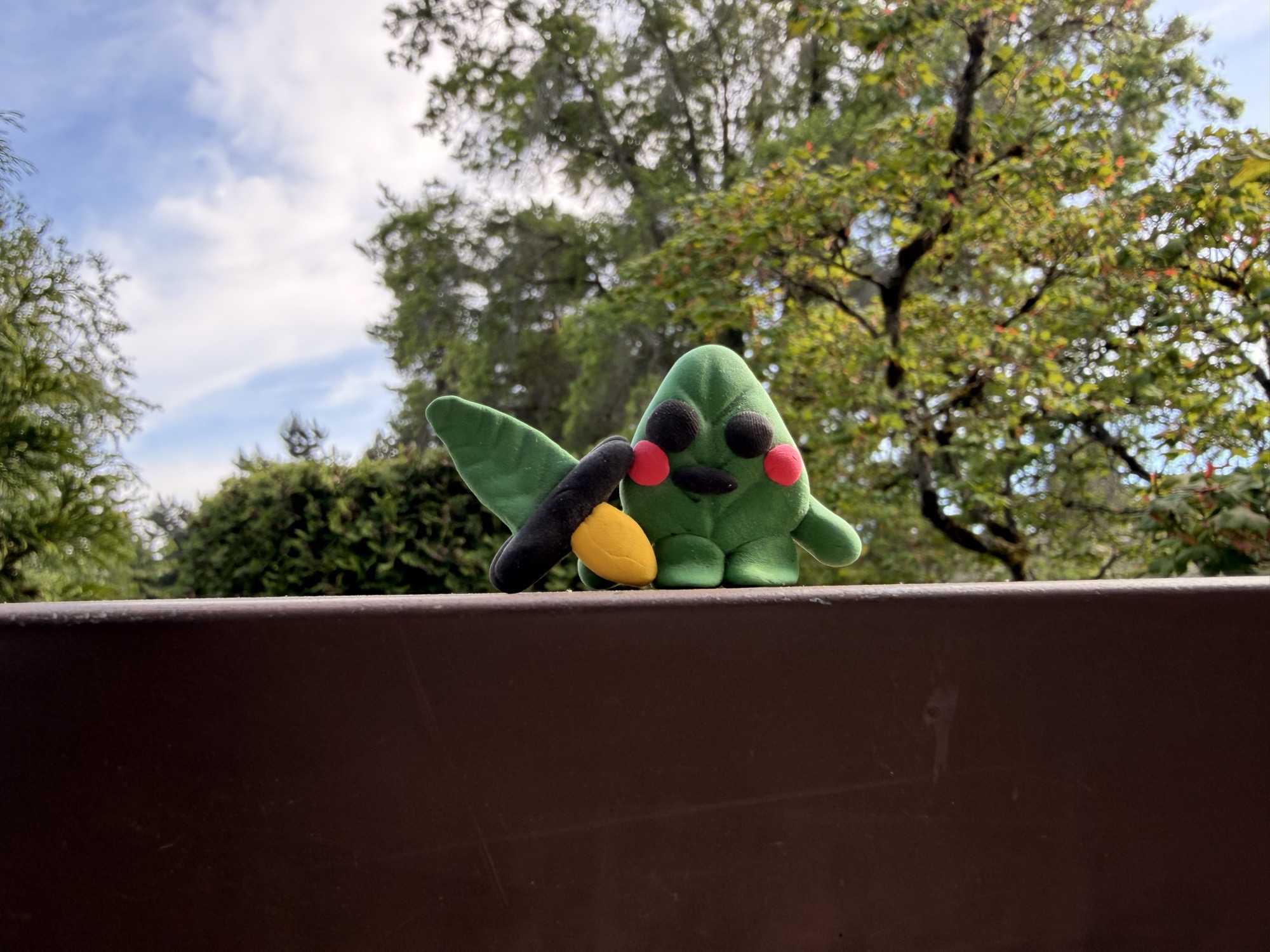A small green handmade character sitting outdoors