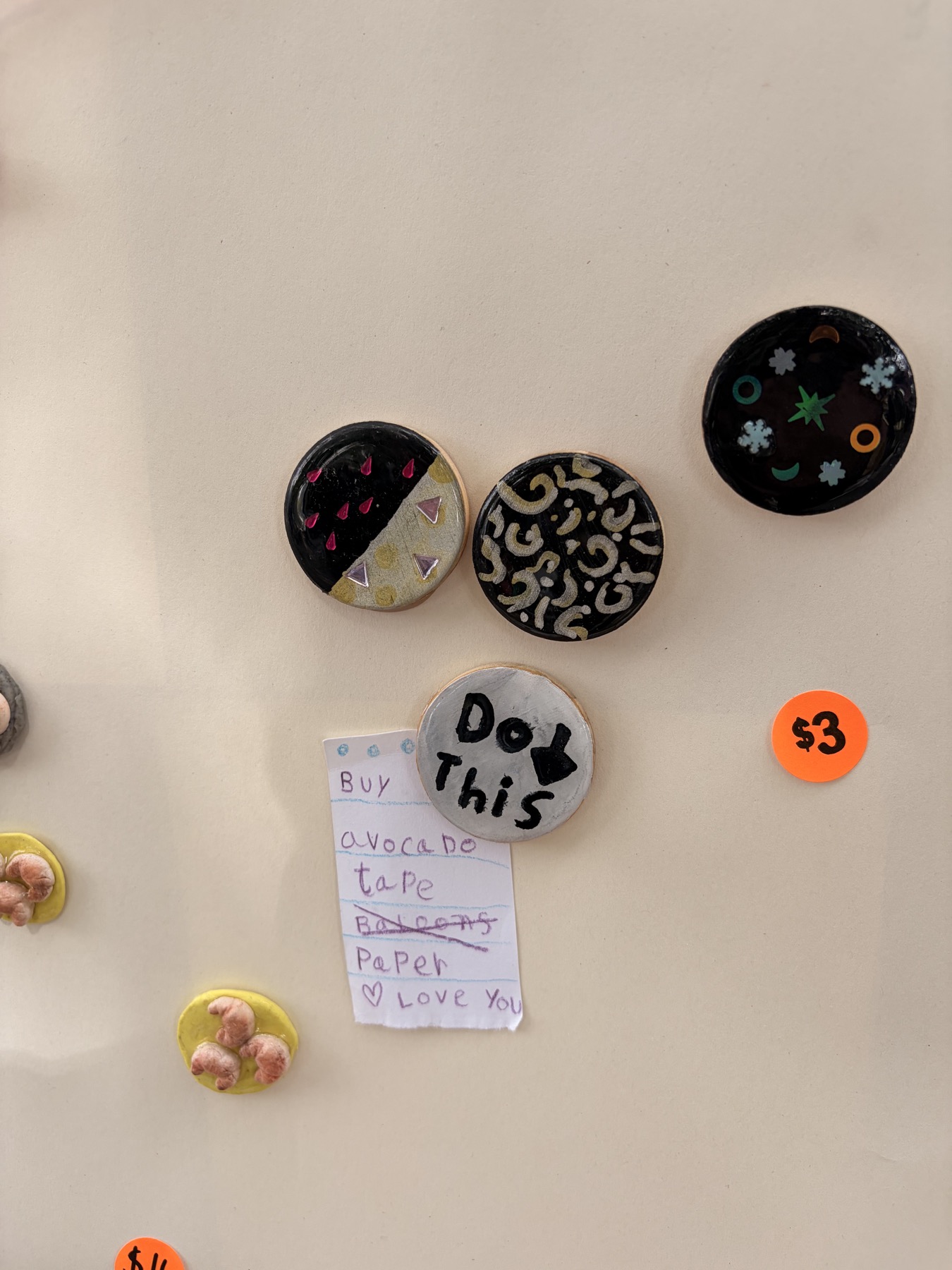 Handmade round art badges and a tiny handwritten note on the craft-sale display