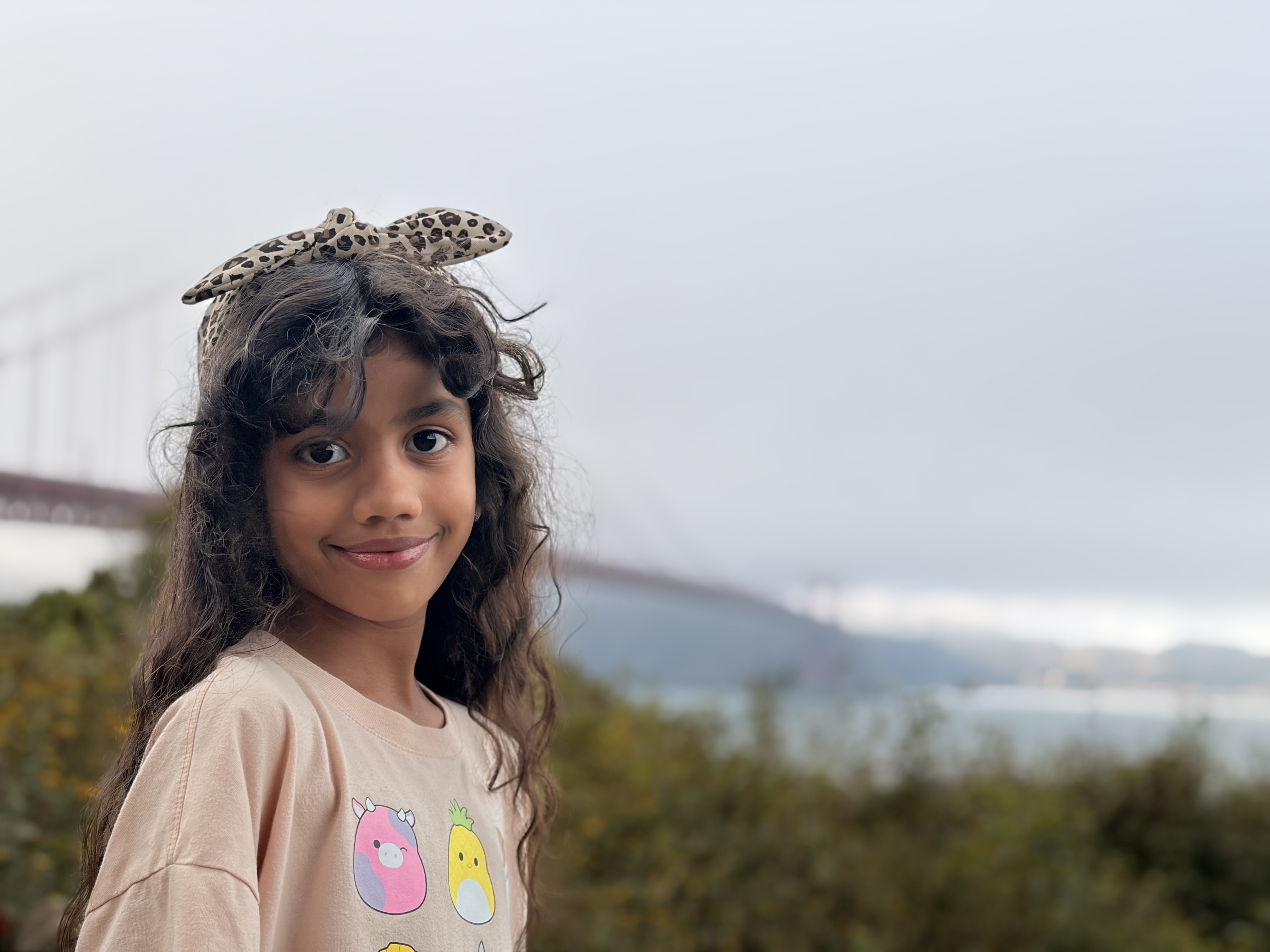 Leela outdoors with mountains and water behind her