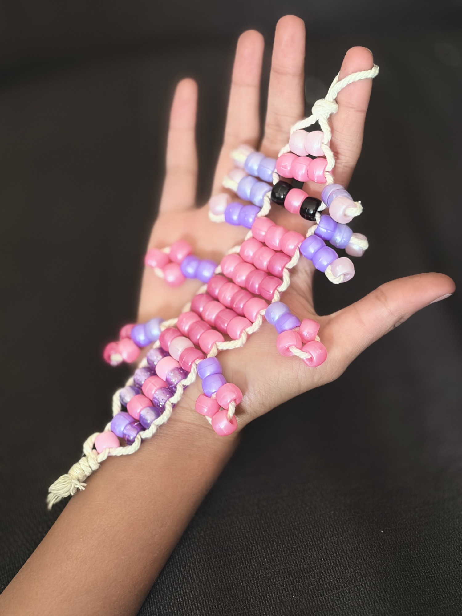 A pink and purple beaded lizard resting on an open hand