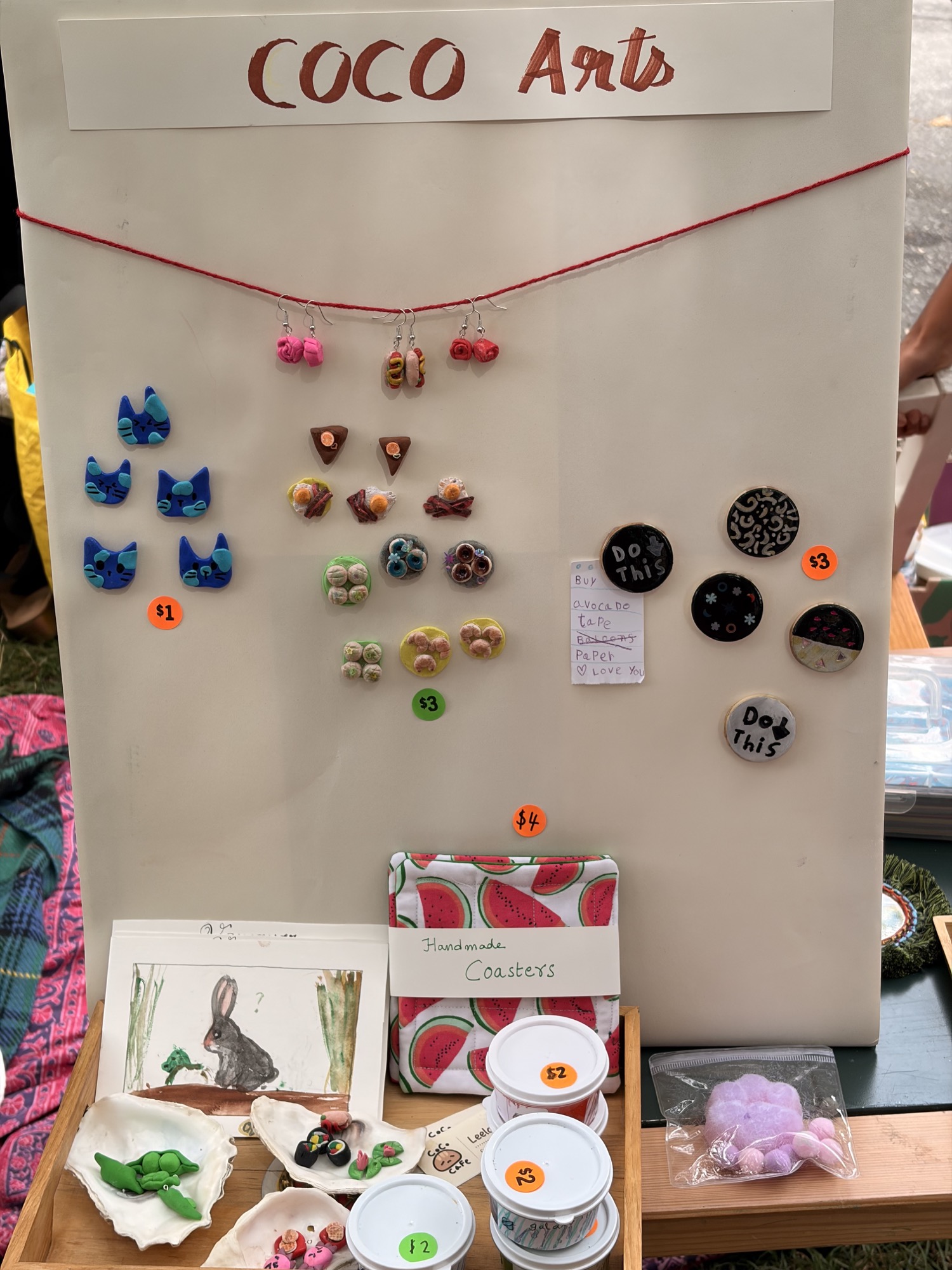 Coco Art display with handmade earrings, cat magnets, paintings, and coasters